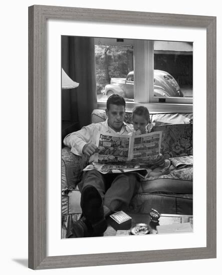 Father Sitting on Couch with Pigtailed Daughter Reading to Her the Sunday Comic Pages-Nina Leen-Framed Photographic Print