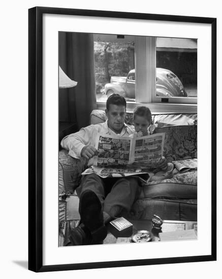 Father Sitting on Couch with Pigtailed Daughter Reading to Her the Sunday Comic Pages-Nina Leen-Framed Photographic Print