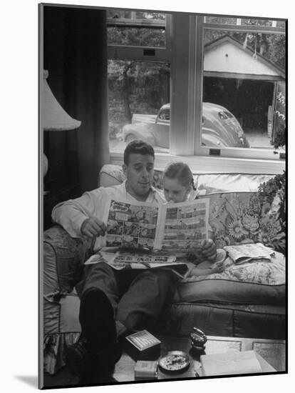 Father Sitting on Couch with Pigtailled Daughter Reading to Her the Sunday Comic Pages-Nina Leen-Mounted Photographic Print