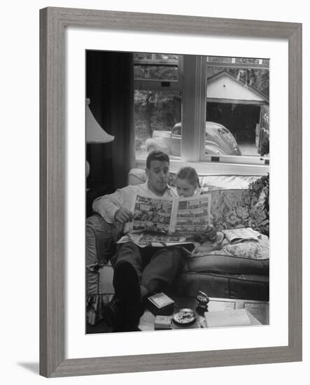 Father Sitting on Couch with Pigtailled Daughter Reading to Her the Sunday Comic Pages-Nina Leen-Framed Photographic Print