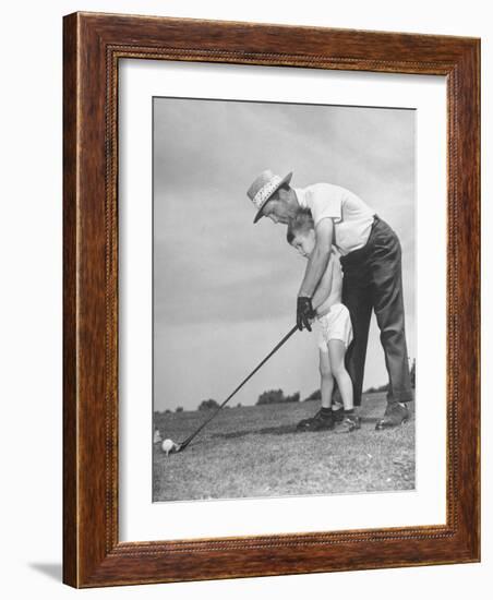 Father Teaching His Small Son How to Play Golf-null-Framed Photographic Print