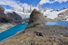 A couple in mountain gear rests on rocks with view to Lago de los Tres and Mount Fitz Roy, Patagoni-Fernando Carniel Machado-Photographic Print