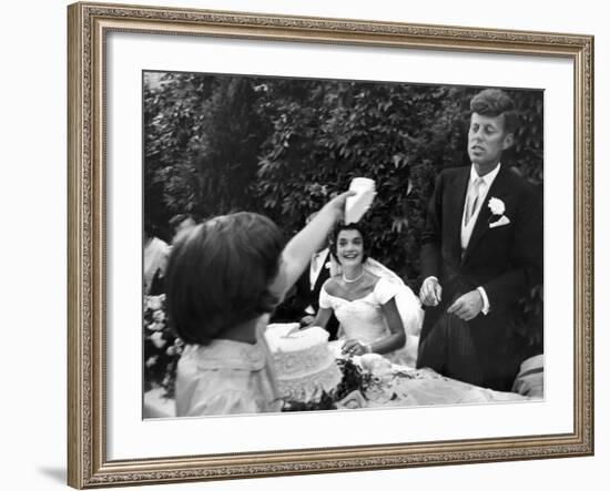 Flower Girl Janet Auchincloss Holding Up a Wedge of Wedding Cake for Bridegroom Sen. John Kennedy-Lisa Larsen-Framed Photographic Print