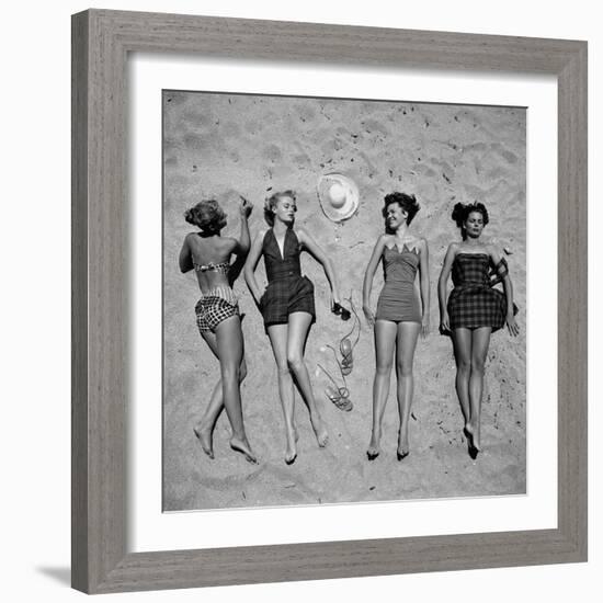 Four Models Showing Off the Latest Bathing Suit Fashions While Laying on a Sandy Florida Beach-Nina Leen-Framed Photographic Print