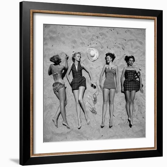 Four Models Showing Off the Latest Bathing Suit Fashions While Laying on a Sandy Florida Beach-Nina Leen-Framed Photographic Print