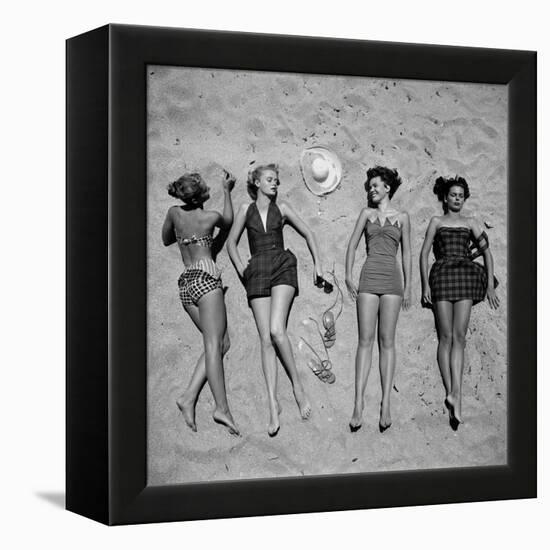 Four Models Showing Off the Latest Bathing Suit Fashions While Lying on a Sandy Florida Beach-Nina Leen-Framed Premier Image Canvas