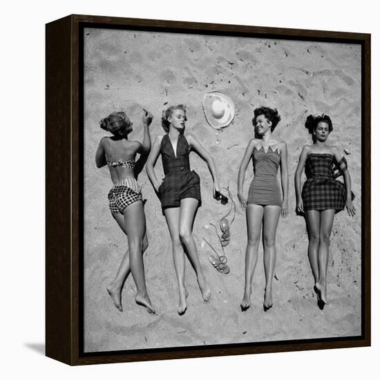 Four Models Showing Off the Latest Bathing Suit Fashions While Lying on a Sandy Florida Beach-Nina Leen-Framed Premier Image Canvas