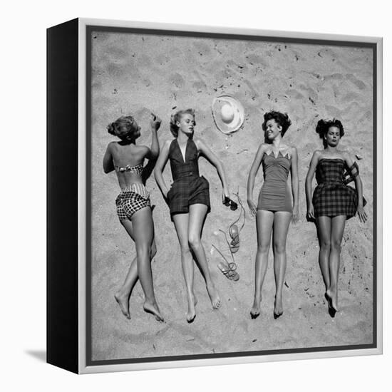 Four Models Showing Off the Latest Bathing Suit Fashions While Lying on a Sandy Florida Beach-Nina Leen-Framed Premier Image Canvas