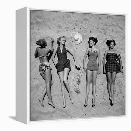 Four Models Showing Off the Latest Bathing Suit Fashions While Lying on a Sandy Florida Beach-Nina Leen-Framed Premier Image Canvas