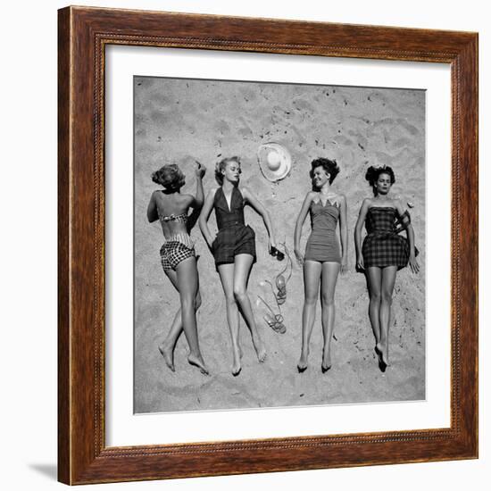 Four Models Showing Off the Latest Bathing Suit Fashions While Lying on a Sandy Florida Beach-Nina Leen-Framed Photographic Print