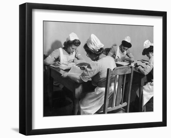 Four Young British Student Nurses Making Notes Together from Medical Textbooks-null-Framed Photographic Print