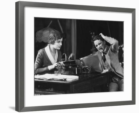Frowning Manager Reviewing Secretary's Work-null-Framed Photo