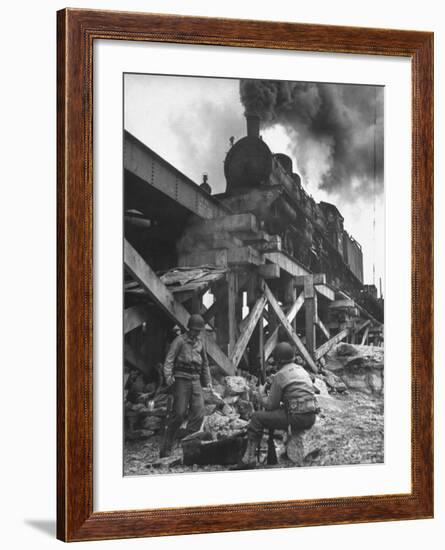 Gi Infantry Guards Keeping Warm by a Fire Next to an Army Engineer Built Railroad Bridge-Ralph Morse-Framed Photographic Print