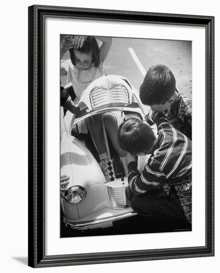 Girl Demurely Adjusting Her Hair While Willing Volunteers Repair Jammed Front Wheels of Her Car-Nina Leen-Framed Photographic Print