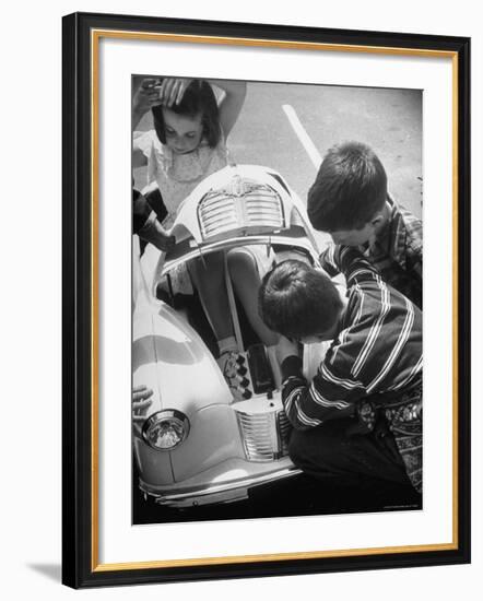 Girl Demurely Adjusting Her Hair While Willing Volunteers Repair Jammed Front Wheels of Her Car-Nina Leen-Framed Photographic Print