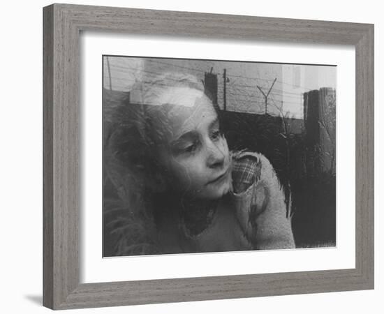 Girl Gazing Pensively Through Pane of Her Apartment Window, Grimly Reflects Image of Berlin Wall-Paul Schutzer-Framed Photographic Print