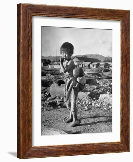 Girl Standing in Rubble from the Korean Civil War, Carrying a Baby in a Sling on Her Back-Joe Scherschel-Framed Photographic Print