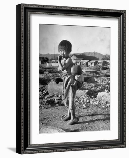 Girl Standing in Rubble from the Korean Civil War, Carrying a Baby in a Sling on Her Back-Joe Scherschel-Framed Photographic Print