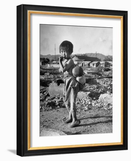 Girl Standing in Rubble from the Korean Civil War, Carrying a Baby in a Sling on Her Back-Joe Scherschel-Framed Photographic Print