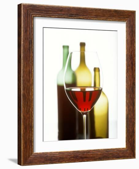 Glass of Red Wine in Front of Three Wine Bottles-Joerg Lehmann-Framed Photographic Print