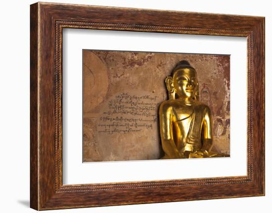 Golden Buddha Statue in Front of Burmese Writing on Wall, Bagan, Myanmar-Harry Marx-Framed Photographic Print