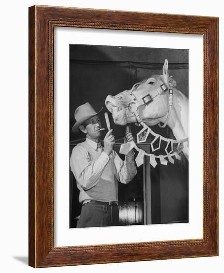 Groom Cleaning Horse's Teeth During Filming of the Movie "The Ziegfeld Follies"-John Florea-Framed Photographic Print