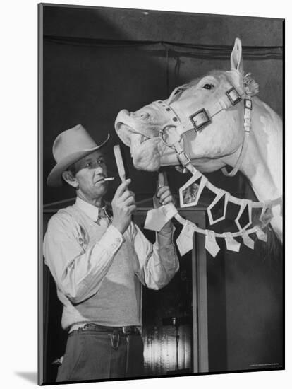 Groom Cleaning Horse's Teeth During Filming of the Movie "The Ziegfeld Follies"-John Florea-Mounted Photographic Print