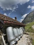 Swiss dairy farm with drying milk cans against Swiss Alps in background-Guy Midkiff-Photographic Print
