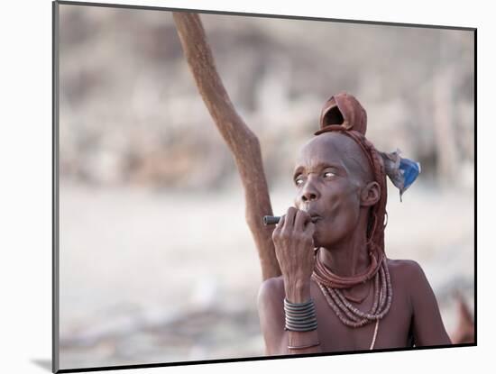 Himba Woman Smokes Outside Her Thatched Home in the Tiny Village, Purros, Namibia, Africa-Kim Walker-Mounted Photographic Print