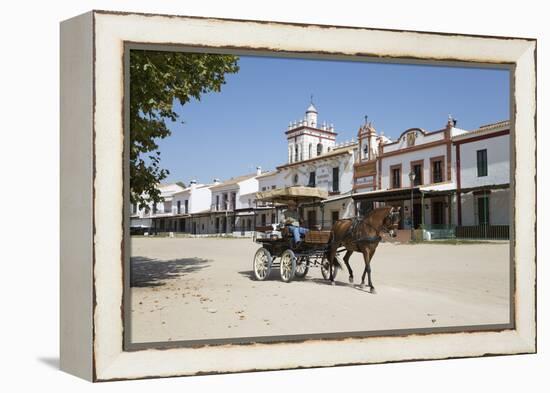 Horse and carriage riding along sand streets with brotherhood houses behind, El Rocio, Huelva Provi-Stuart Black-Framed Premier Image Canvas