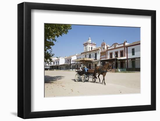 Horse and carriage riding along sand streets with brotherhood houses behind, El Rocio, Huelva Provi-Stuart Black-Framed Photographic Print