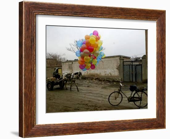 Horse Drawn Cart Drives Past as Balloons Tied to a Bicycle Flutter in the Wind-null-Framed Photographic Print