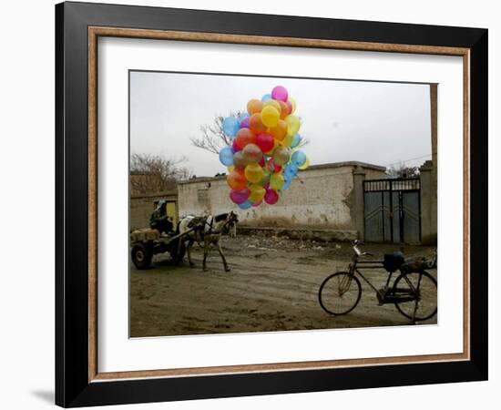 Horse Drawn Cart Drives Past as Balloons Tied to a Bicycle Flutter in the Wind-null-Framed Photographic Print