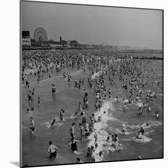 Huge Crowd Gathered in the Surf and at the Beach in Front of Coney Island Amusement Park-Marie Hansen-Mounted Photographic Print