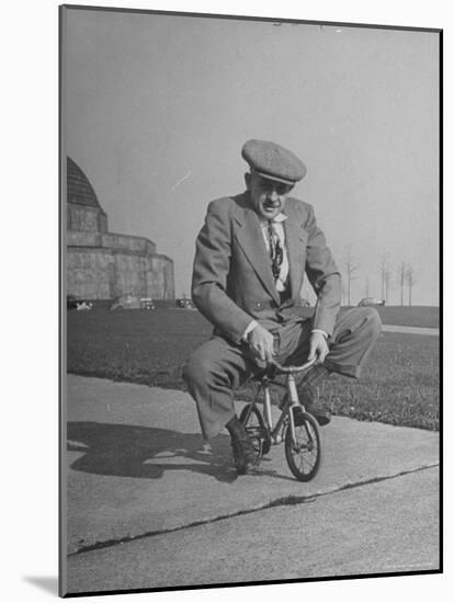 Humorous of Man Riding Tiny Bicycle-Wallace Kirkland-Mounted Photographic Print