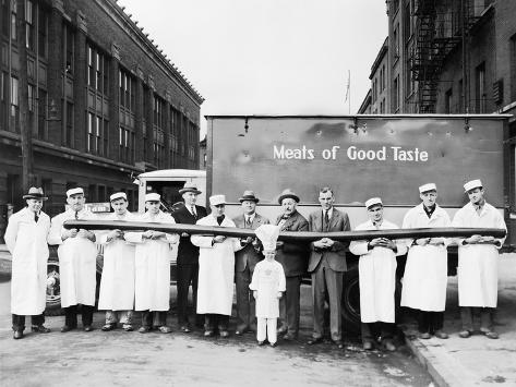 Photo: Butchers Showing Off a Long Sausage in Front of a Truck: 24x18in