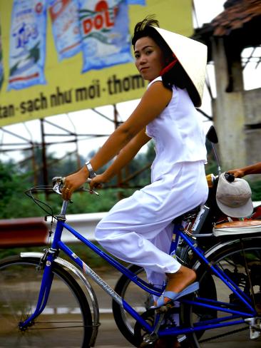 Photographic Print: Vietnamese woman cycles in white clothes and hat by Charles Bowman: 24x18in