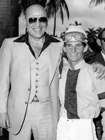 Photographic Print: Actor Telly Savalas Poses with a Jockey at Hialeah Park, C.1970: 24x18in