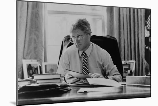 Informal Portrait of President Bill Clinton at His Desk in the Oval Office-null-Mounted Premium Photographic Print