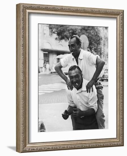 Italian Man Leaping Onto a Friend's Back in Casual Greeting While Crossing a Piazza-Paul Schutzer-Framed Photographic Print