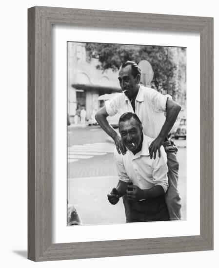 Italian Man Leaping Onto a Friend's Back in Casual Greeting While Crossing a Piazza-Paul Schutzer-Framed Photographic Print