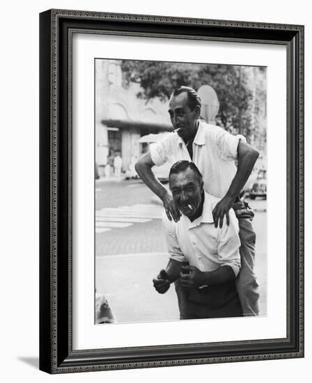 Italian Man Leaping Onto a Friend's Back in Casual Greeting While Crossing a Piazza-Paul Schutzer-Framed Photographic Print