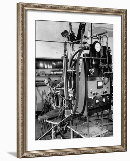 Italian Physicist Enrico Fermi Peering Out from Behind Large, Complicated Machinery in Laboratory-Ralph Morse-Framed Premium Photographic Print