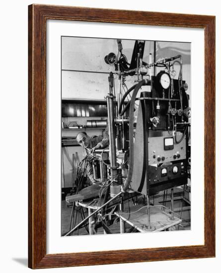 Italian Physicist Enrico Fermi Peering Out from Behind Large, Complicated Machinery in Laboratory-Ralph Morse-Framed Premium Photographic Print