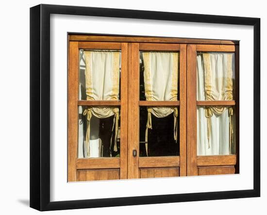 Italy, Tuscany, Monticchiello. Yellow curtains hanging in a window of a shop.-Julie Eggers-Framed Photographic Print