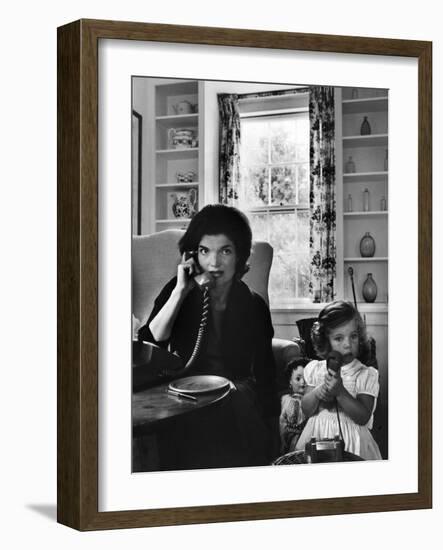 Jackie Kennedy, Wife of Senator John Kennedy, Talking on the Telephone as her daughter mimics her-Alfred Eisenstaedt-Framed Photographic Print