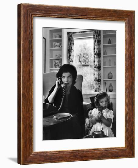 Jackie Kennedy, Wife of Senator John Kennedy, Talking on the Telephone as her daughter mimics her-Alfred Eisenstaedt-Framed Photographic Print