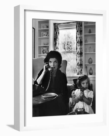 Jackie Kennedy, Wife of Senator John Kennedy, Talking on the Telephone as her daughter mimics her-Alfred Eisenstaedt-Framed Photographic Print