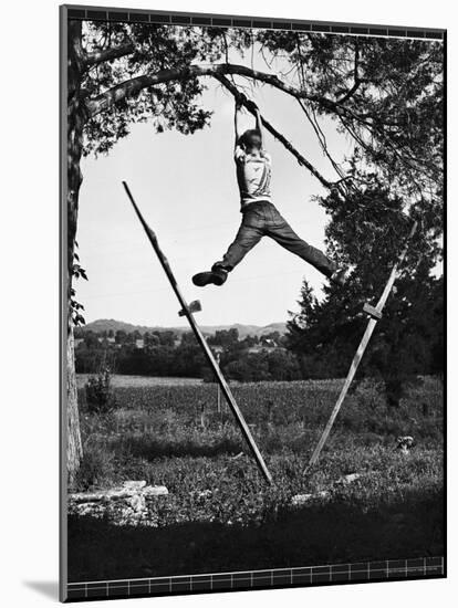 Kenneth Merriman Swinging on Tree Limb After Kicking Away Stilts-Robert W^ Kelley-Mounted Photographic Print