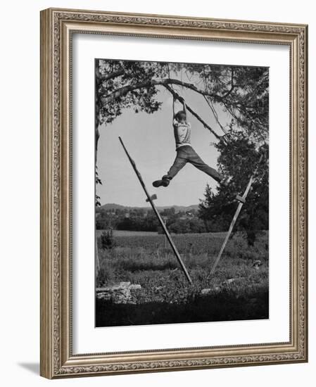 Kenneth Merriman Swinging on Tree Limb after Kicking Away Stilts-null-Framed Photographic Print